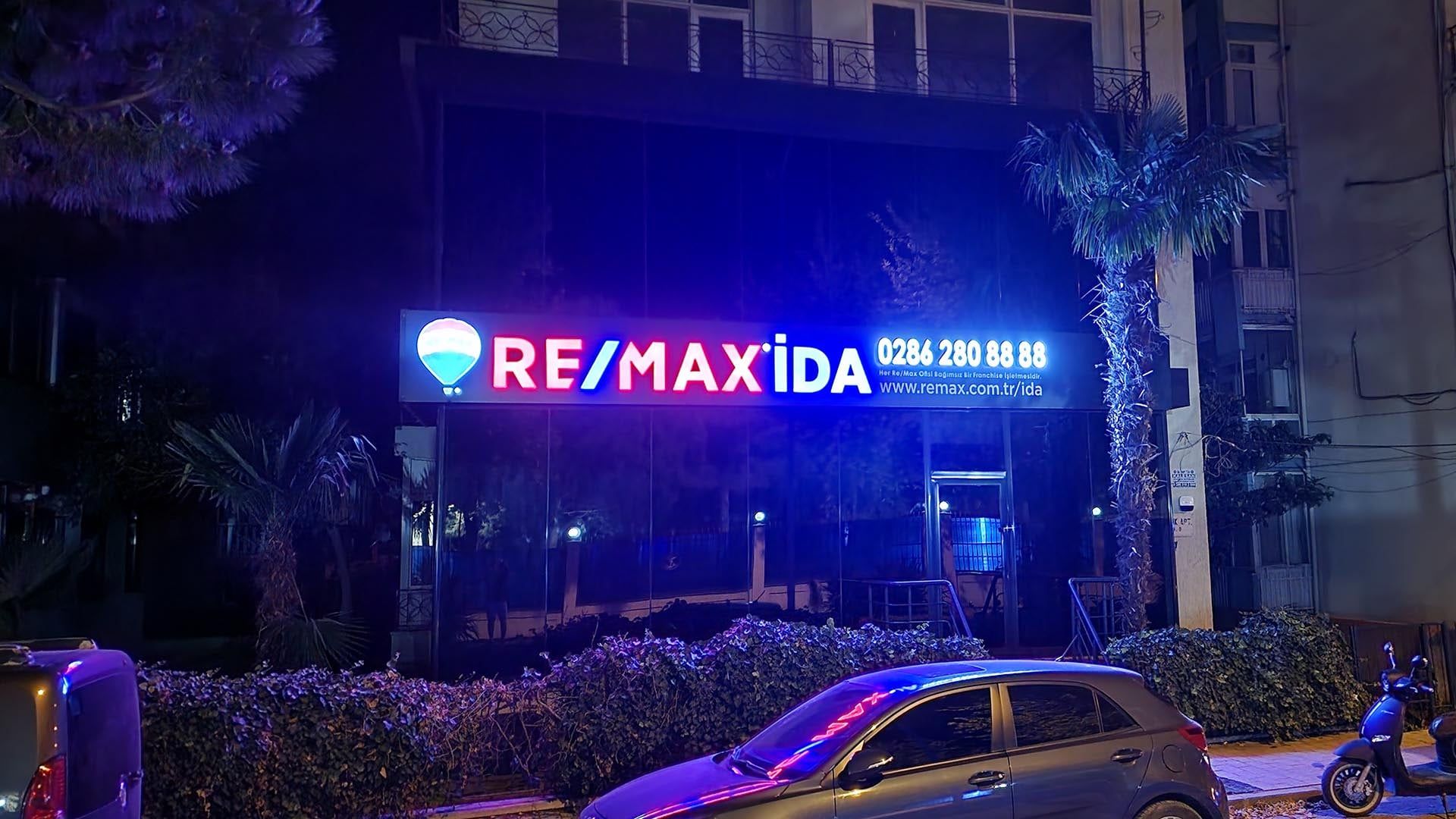 Das beleuchtete Schild des Büros von RE/MAX İDA bei Nacht